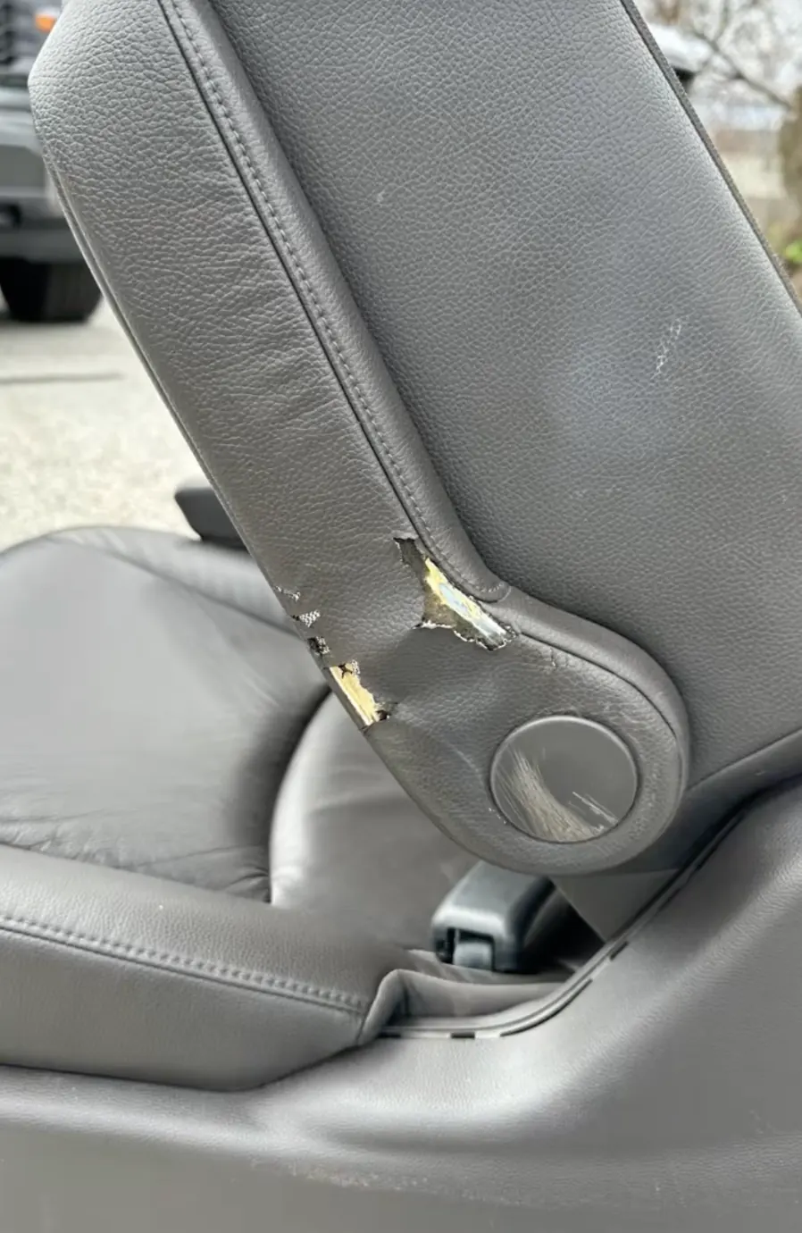 Torn gray leather on a seat back bolster beside the recliner before leather seat repair