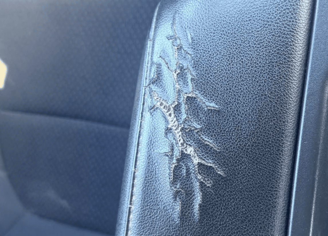 Cracked leather car seat before mobile upholstery repair at dealership