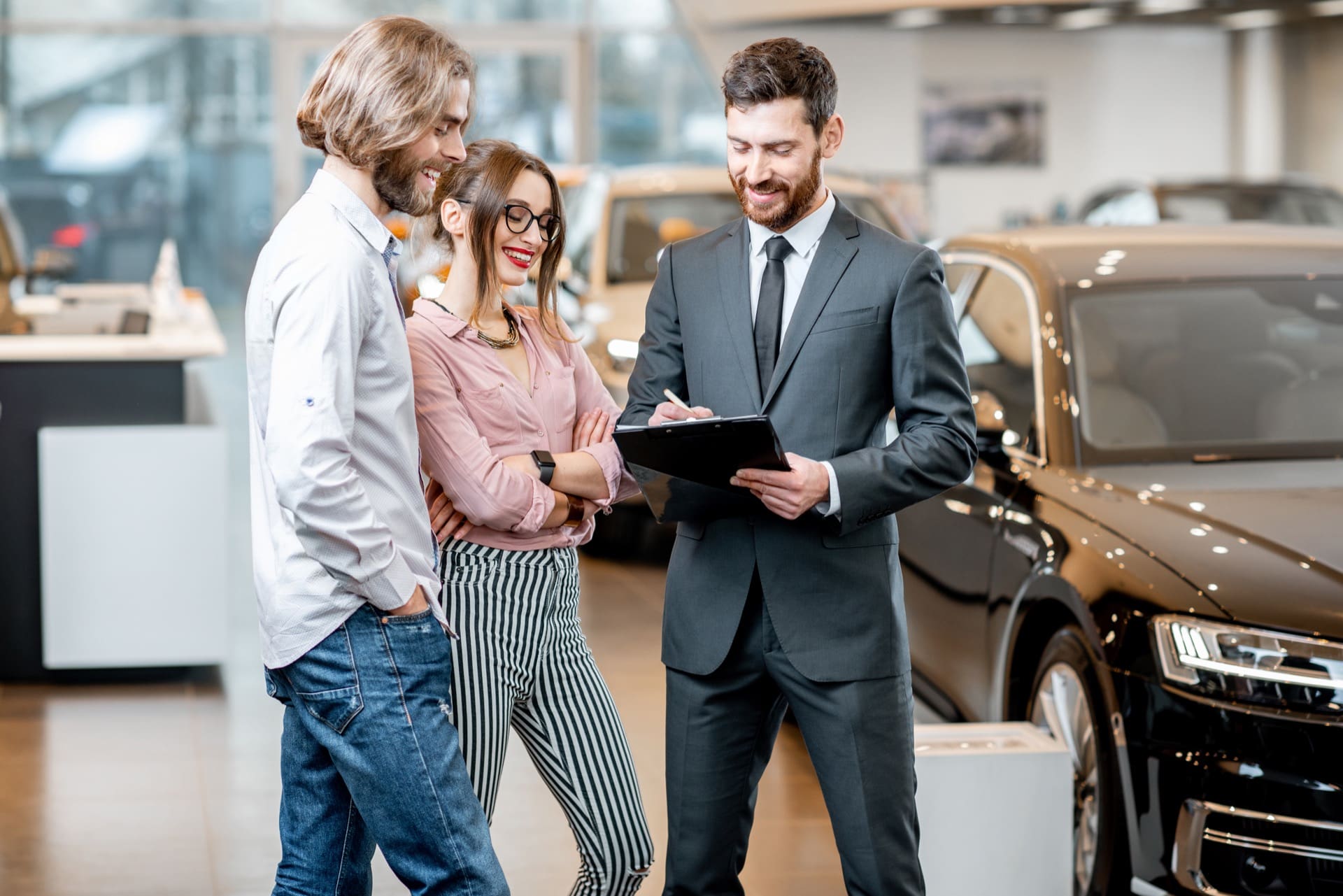 Car salesman with customers in Philadelphia dealership showroom