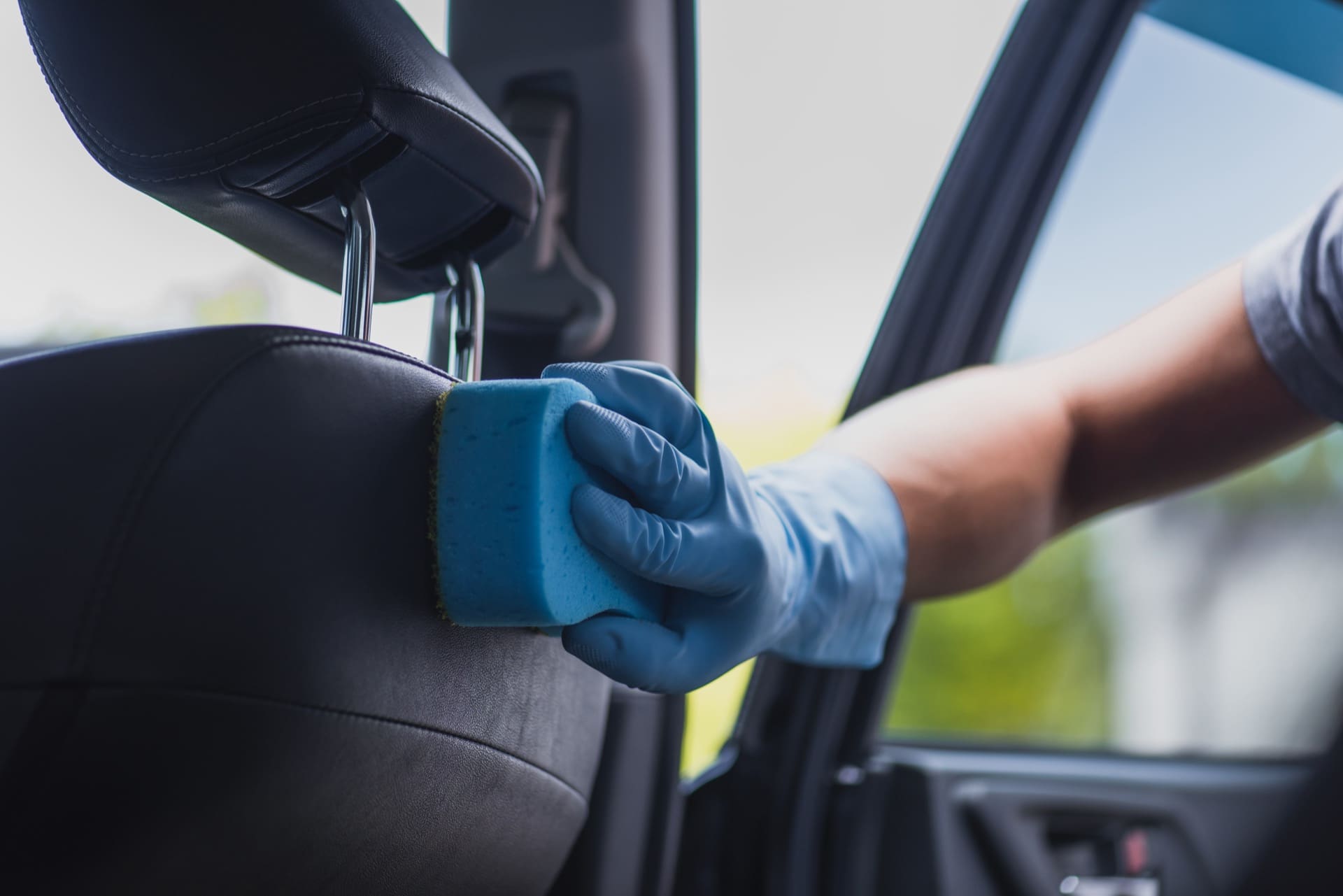 Technician wiping down car seats during interior and exterior detailing in Allentown