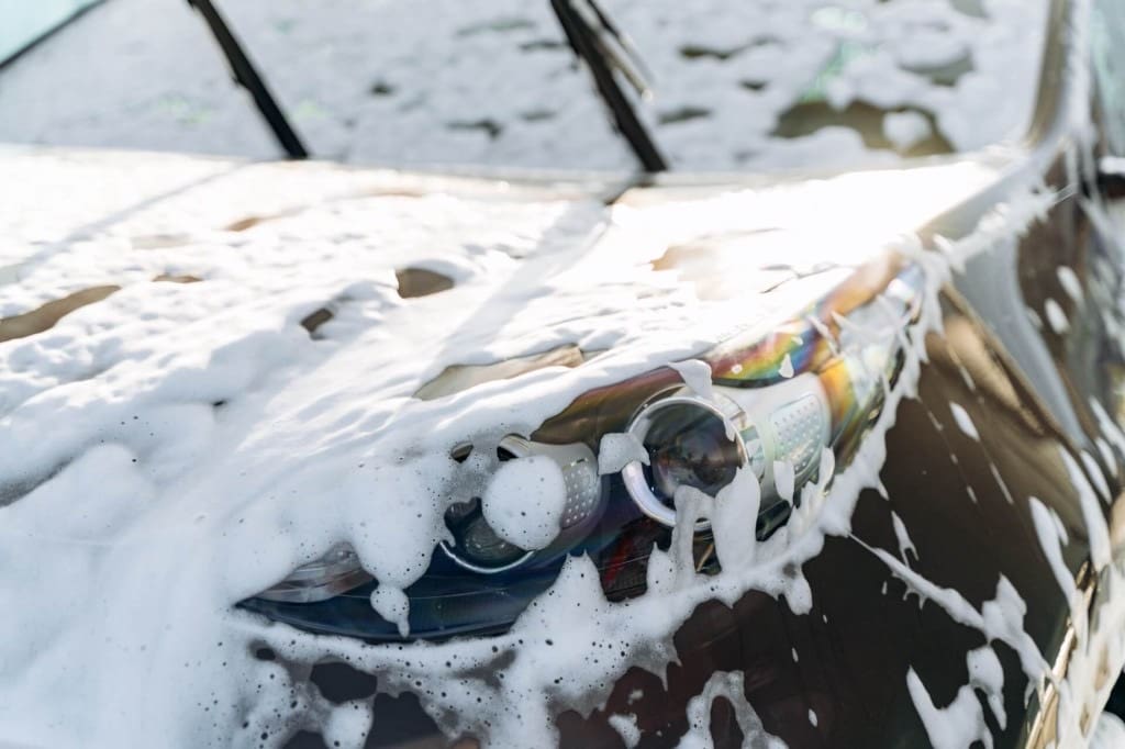 Mobile detailing in York PA: snow foam wash on a dark vehicle headlight and hood